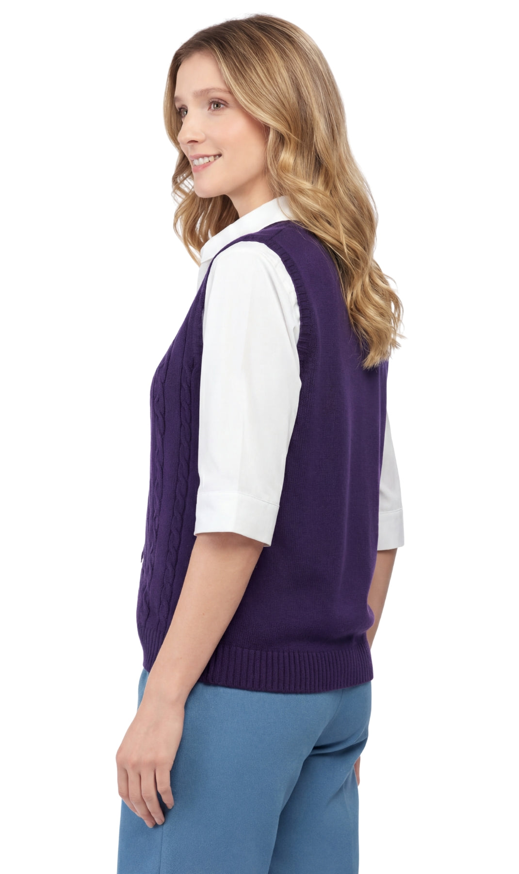 Woman wearing a purple sweater vest over a white shirt and blue pants on a white background