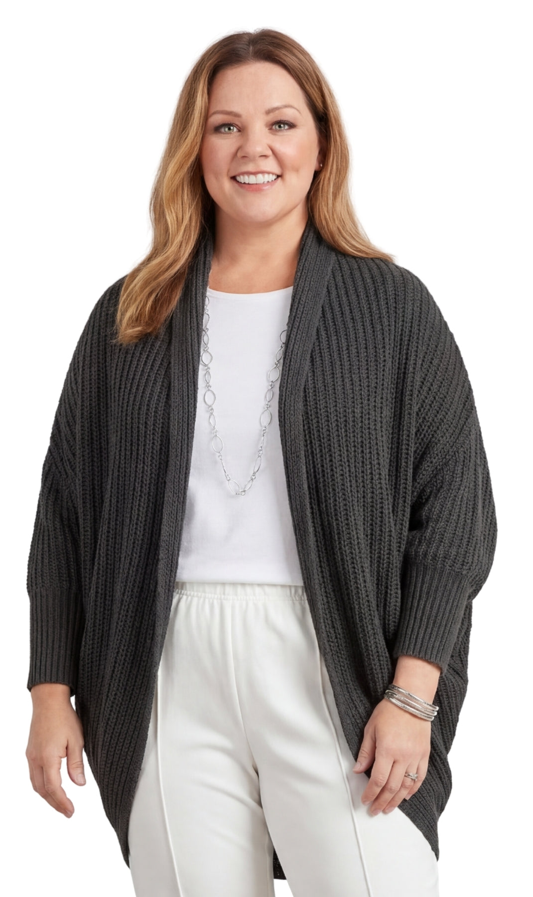 Woman wearing a dark gray cardigan over a white top and pants on a white background